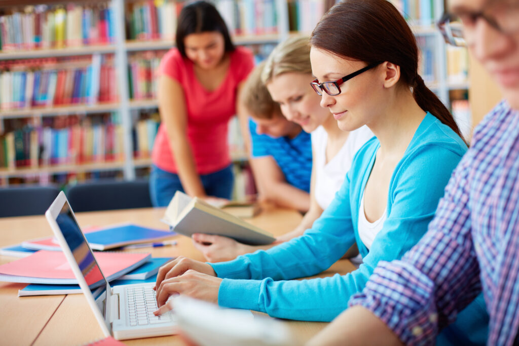 Portrait of pretty girl typing on laptop among her group mates at lesson